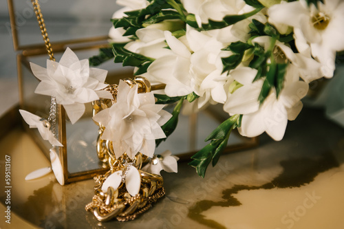 Beautiful golden earrings next to flowers, interior details of a women's bedroom