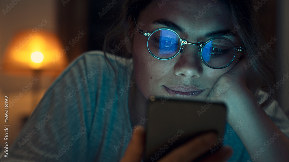 Woman using mobile phone while laying on bed at night