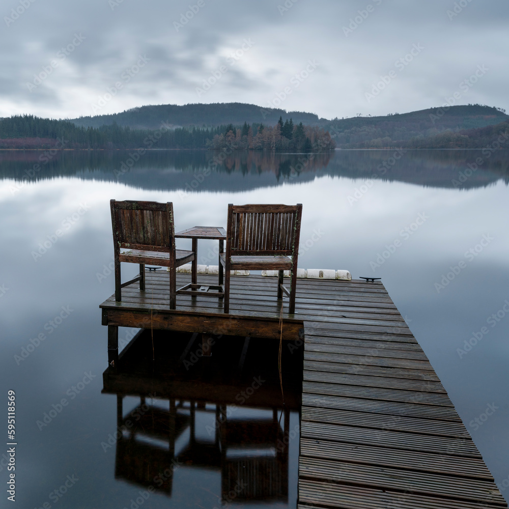 Naklejka premium Two Wooden chairs ont eh waterside jetty Scotland