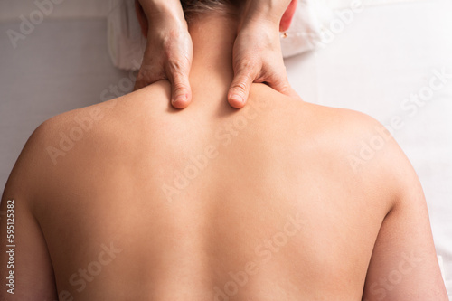 masseur massaging back and shoulder blades of young woman on massage table. Concept of massage spa treatments. Close-up