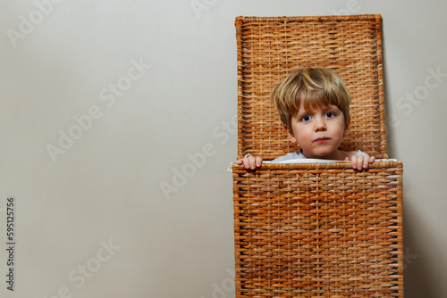 Close portrait of a boy play hide-and-seek in laundry box