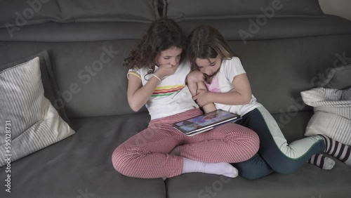 4K footage of alone girls sitting on sofa watching inappropriate content on tablet and getting scared
