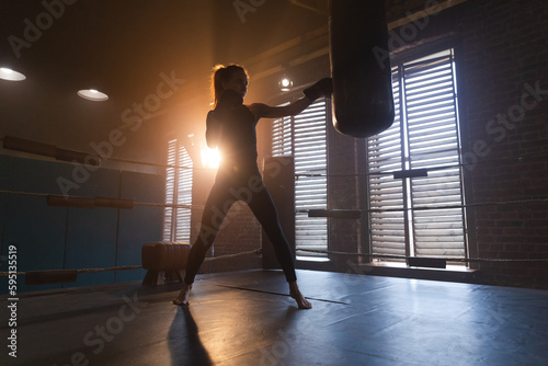 Fototapeta Naklejka Na Ścianę i Meble -  Women self defense girl power. Strong woman fighter training punches on boxing ring. Healthy strong girl punching boxing bag. Training day in boxing gym. Strength fit body workout training