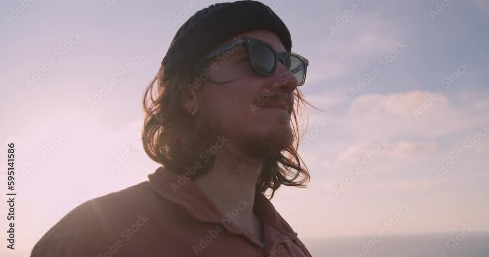 Young, bearded man watching the sunset and waves rolling in along the coastline and cliffs of the Western Algarve, Portugal Young, bearded man watching the sunset and waves rolling in along the coastline and cliffs of the Western Algarve, Portugal