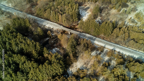 An aerial drone shot of a train track crossing a creek in the winter