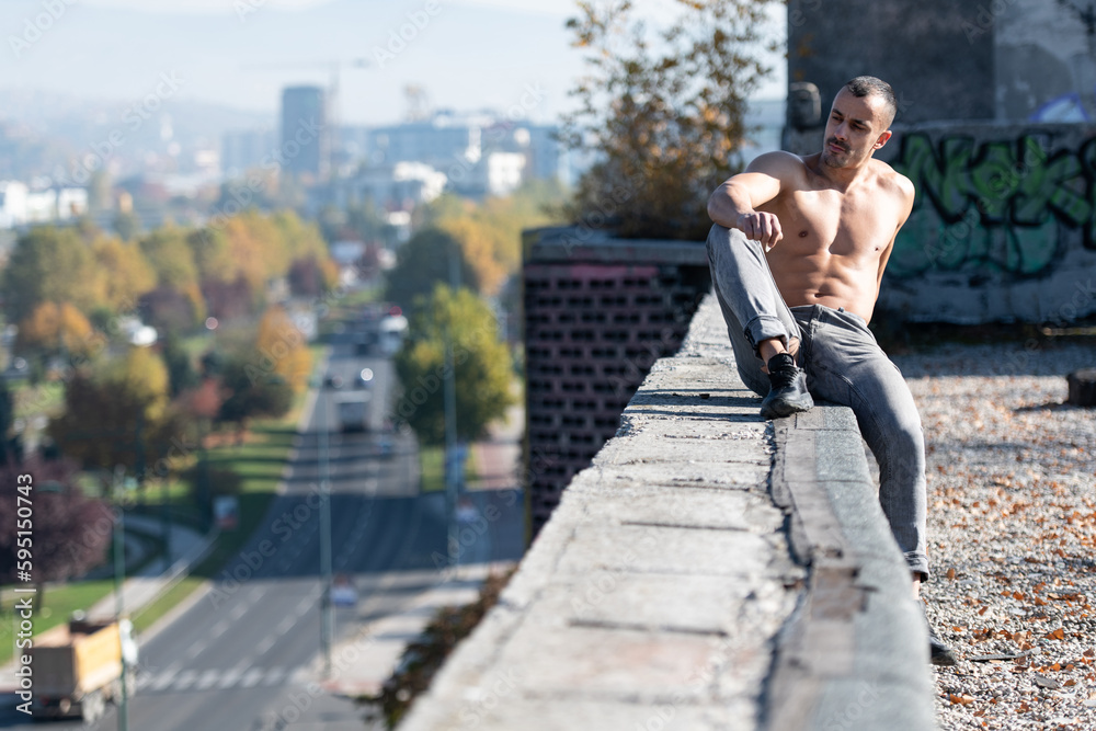 Portrait of Muscular Man Sitting on Old Rooftop