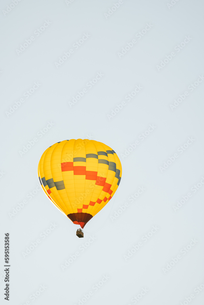 Naklejka premium Low angle view of yellow hot air balloon in Sedona Arizona isolated against light blue sky background in early morning.
