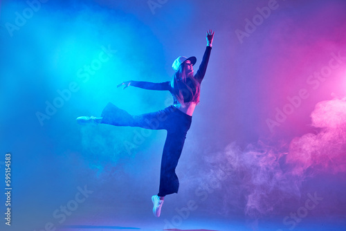 a girl in dark clothes dances on a neon background in smoke, modern dance