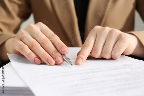 Woman signing document at table, closeup view