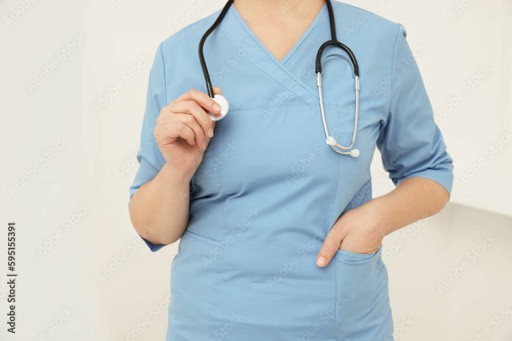 Professional doctor with stethoscope indoors, closeup view Professional doctor with stethoscope indoors, closeup view