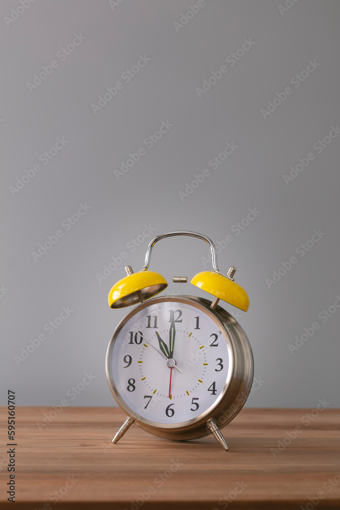 Retro silver alarm clock. 11:00. am, pm. Neutral background. Brown wood surface. Vertical photography with empty space for text or image. Retro silver alarm clock. 11:00. am, pm. Neutral background. Brown wood surface. Vertical photography with empty space for text or image.