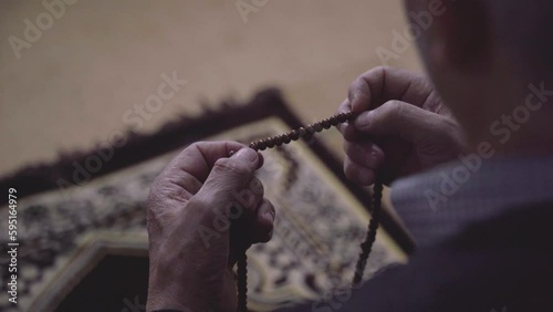 Muslim man hand holding prayer beads, hands in prayer rope, brown rosary beads photo