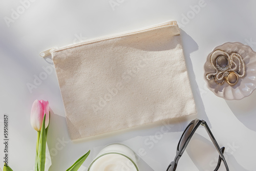 Canvas pouch mock-up. Beige cosmetic bag and feminine accessories on the table