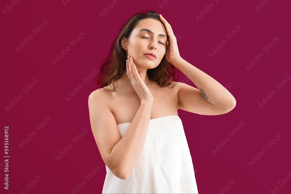 Young brunette woman in towel on pink background
