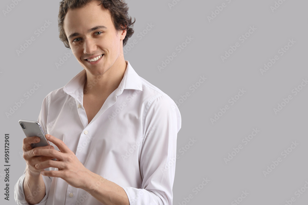 Young man using mobile phone on grey background Young man using mobile phone on grey background
