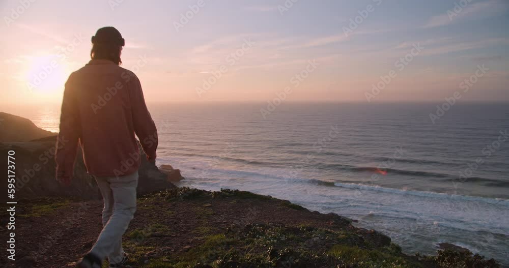 Young, bearded man watching the sunset and waves rolling in along the coastline and cliffs of the Western Algarve, Portugal Young, bearded man watching the sunset and waves rolling in along the coastline and cliffs of the Western Algarve, Portugal