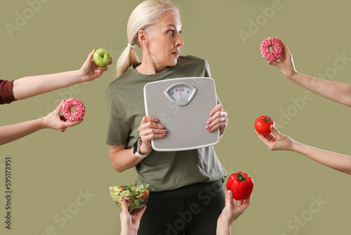 Fotografie Sporty mature woman holding scales and female hands with food on green backgroun