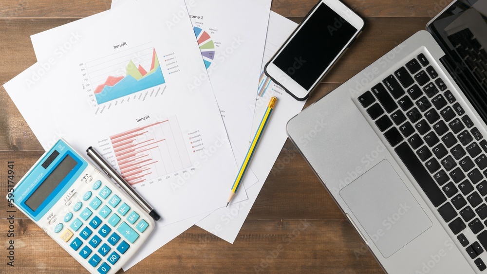 On the work desk, there are several business accessories and charts. On the work desk, there are several business accessories and charts.
