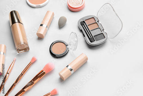 Decorative cosmetics with sponge and brushes on light background