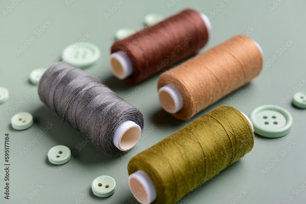 Composition with thread spools and buttons on grey background, closeup Composition with thread spools and buttons on grey background, closeup