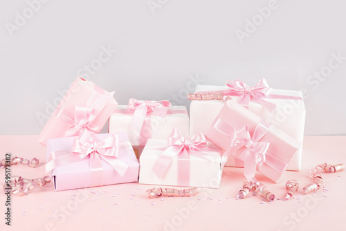 Gift boxes with bows, confetti and serpentine on pink background
