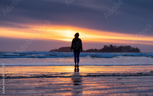 Adventurous Woman Standing on the Sandy Beach on the West Coast of Pacific Ocean. Cox Bay in Tofino, Vancouver Island, BC, Canada. Adventure Travel