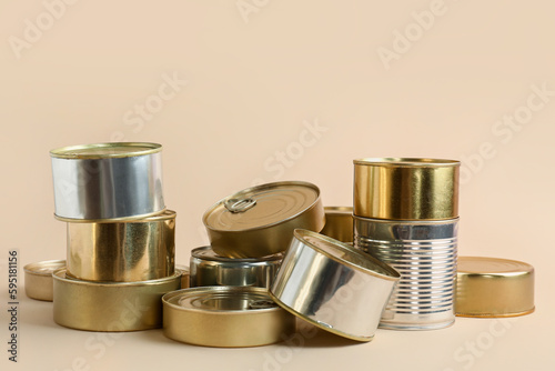 Different tin cans with fish on beige background