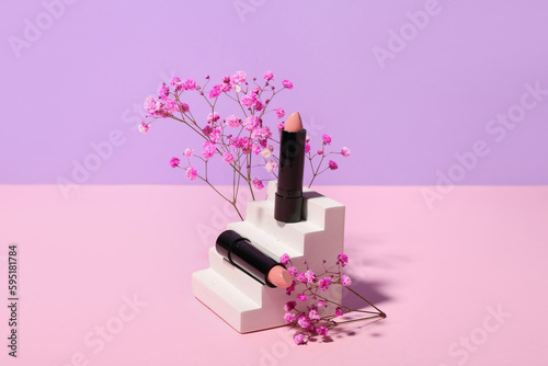 Plaster podium with lipsticks and gypsophila flowers on lilac background