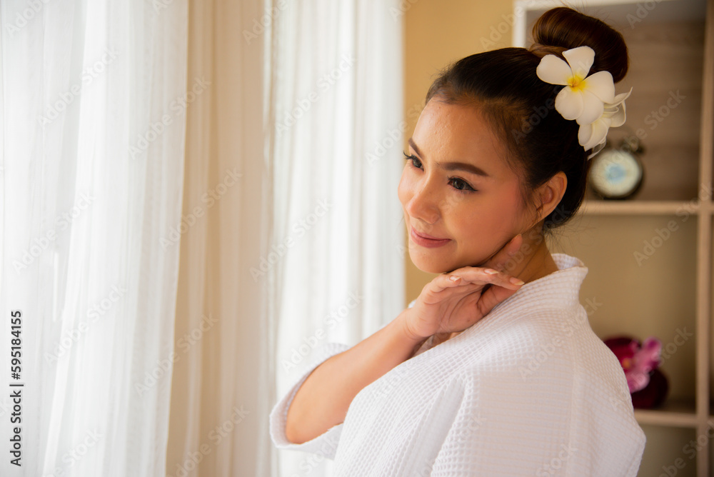 Beautiful asian woman in a white dress standing in front of a window with a smile on her face in soft light at the spa. Beautiful asian woman in a white dress standing in front of a window with a smile on her face in soft light at the spa.