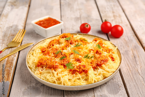 Plate of tasty Italian pasta with Parmesan cheese on light wooden background