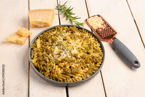 Plate of tasty Italian pasta with Parmesan cheese on light wooden background