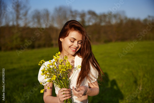 portrait of a happy woman with a bouquet of buttercups walking in the field