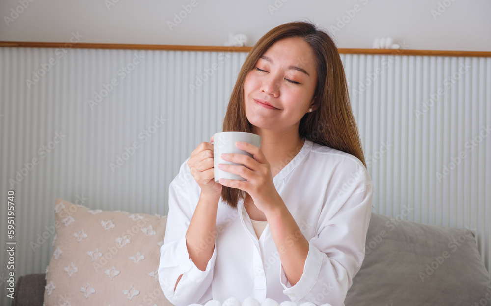 Portrait image of a beautiful woman with closed eyes holding and drinking hot coffee at home Portrait image of a beautiful woman with closed eyes holding and drinking hot coffee at home