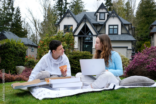 online learning outdoors boys girl sitting gadget outdoors picnic eating pizza learning lessons homework with a laptop in hands communication problem solving serious faces friends classmates