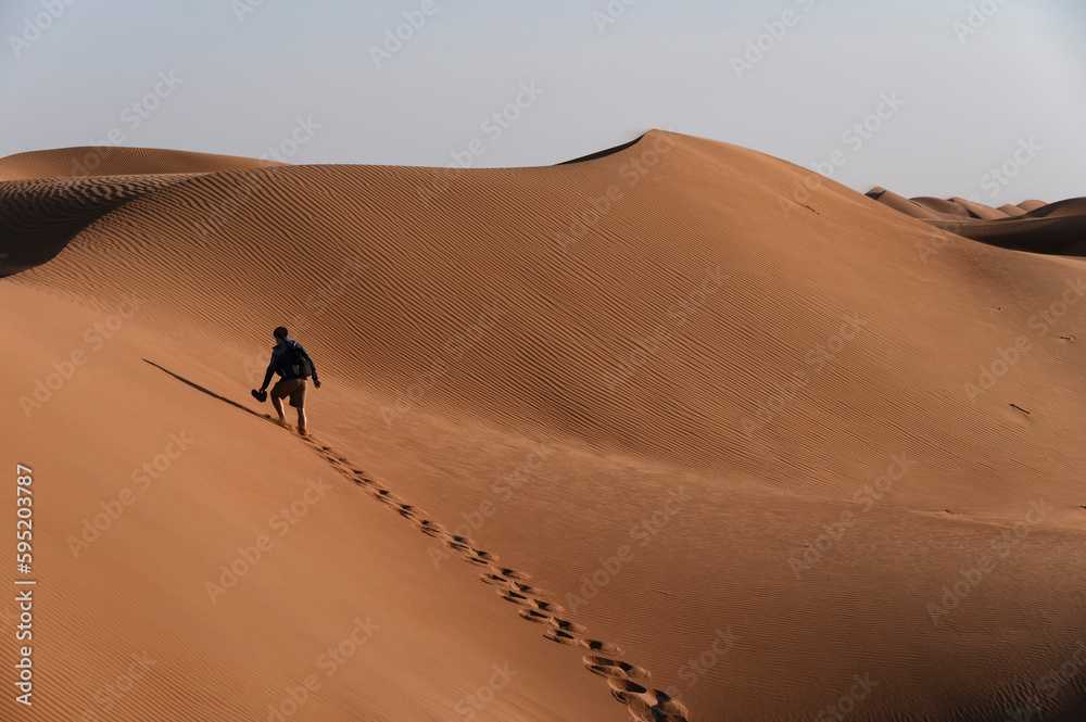 Silhouette of people watching sunset on sand dunes of Wahiba Sands