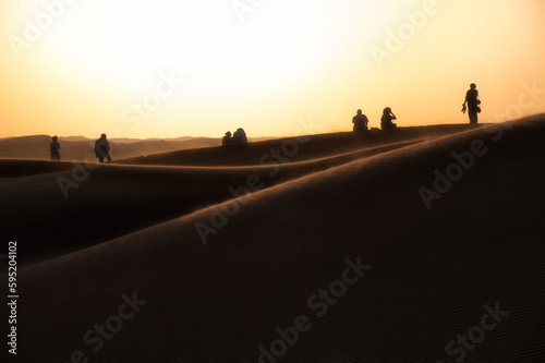 Silhouette of people watching sunset on sand dunes of Wahiba Sands © tapanuth