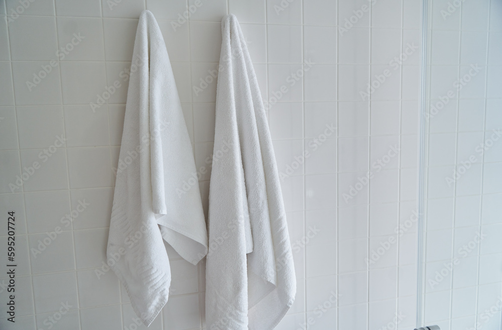 Two white towels hanging in the hotel shower room. High quality photo