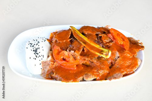 Turkish and Arabic Traditional Ramadan doner kebab with tasty tomato sauce and rice or turkish pilav in white plate on wood table background. ( Pilav ustu doner) photo