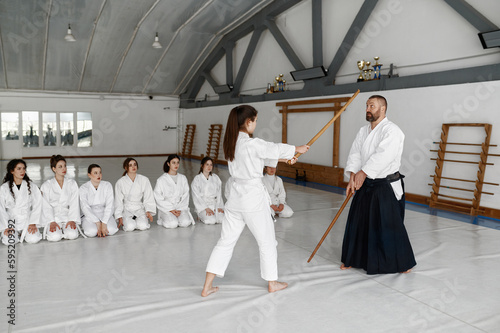 Girl and aikido master fighting with wooden sword during martial arts class
