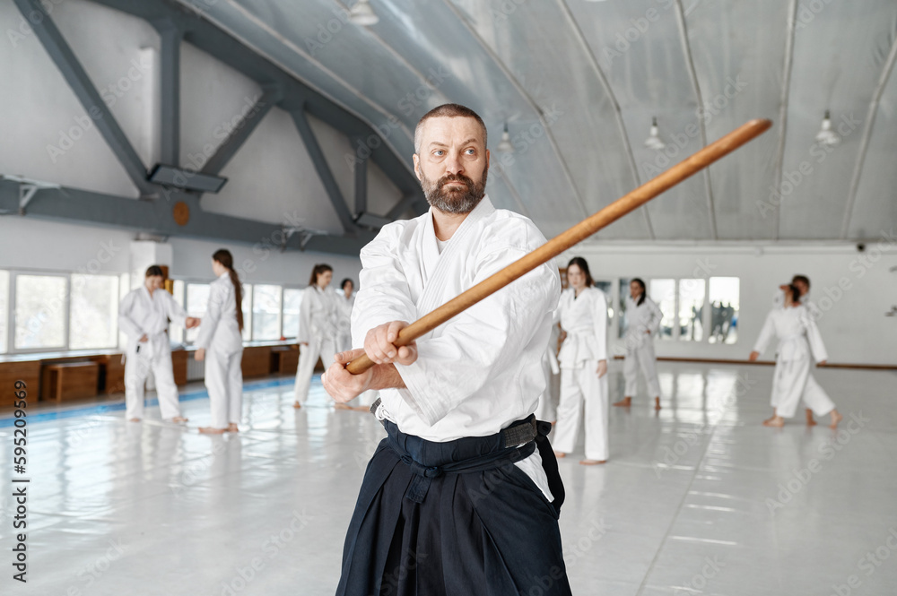 Portrait of aikido sensei master with wooden sword at group training