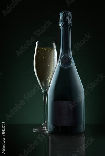 Champagne blank bottle and glass against dark green background