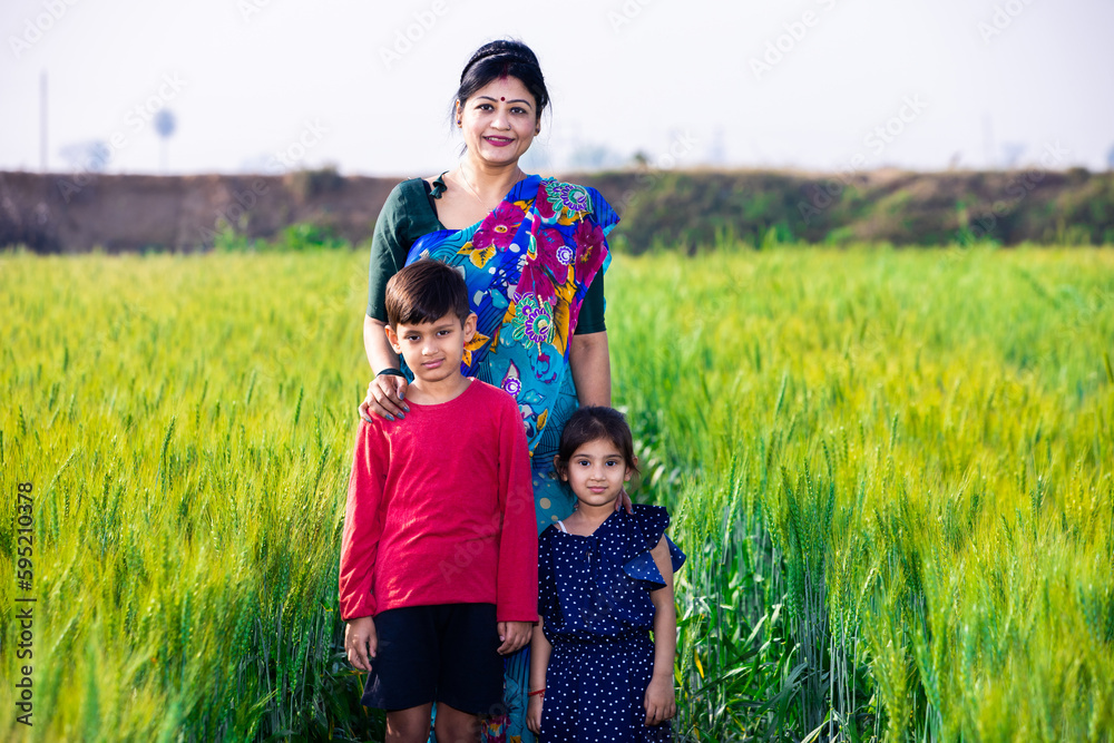 Happy young traditional indian mother standing with her children at wheat agriculture field, Rural india concept. Happy young traditional indian mother standing with her children at wheat agriculture field, Rural india concept.