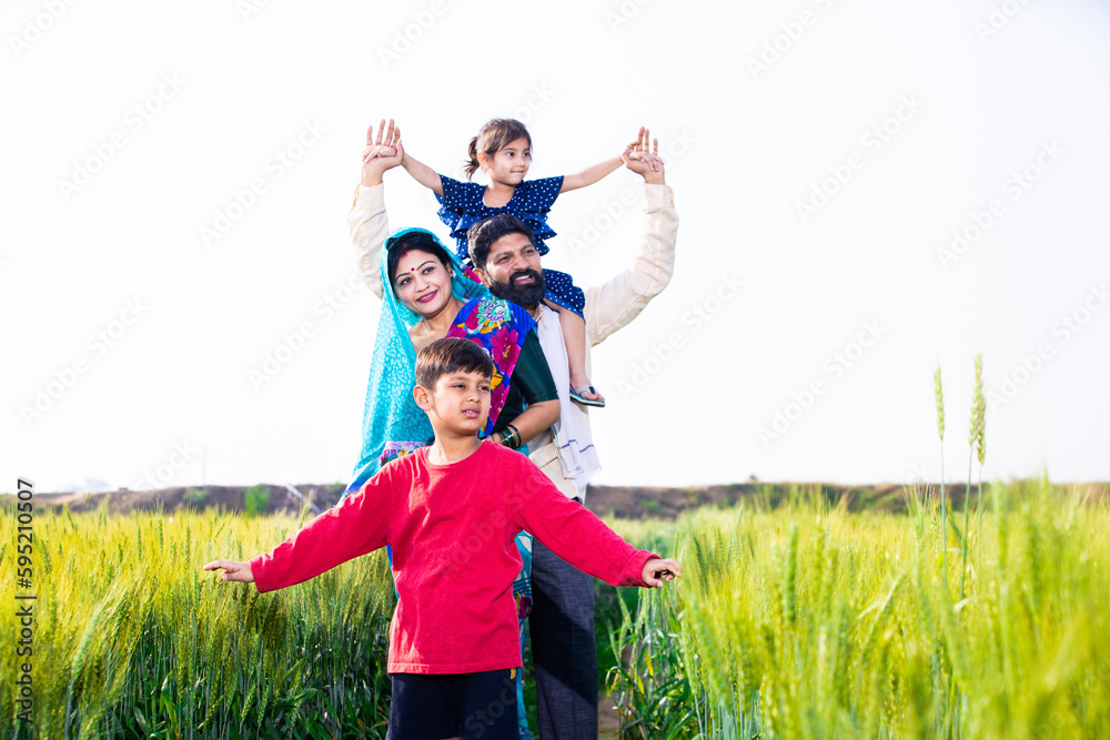 Portrait of happy young indian farmer family standing at wheat agriculture field, Parents with children outdoor, Rural india concept. Copy space Portrait of happy young indian farmer family standing at wheat agriculture field, Parents with children outdoor, Rural india concept. Copy space