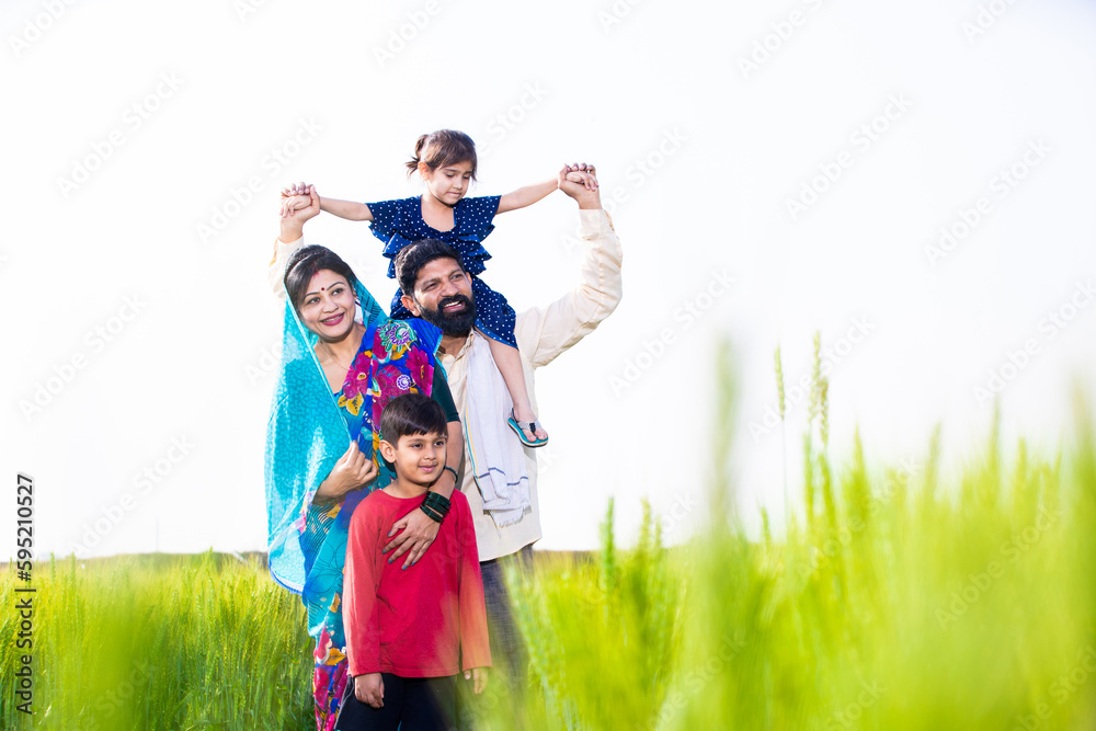 Portrait of happy young indian farmer family standing at wheat ...