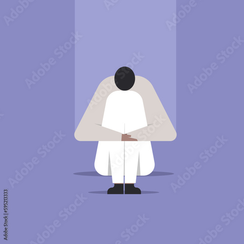 A depressed person with his head down sitting on the floor