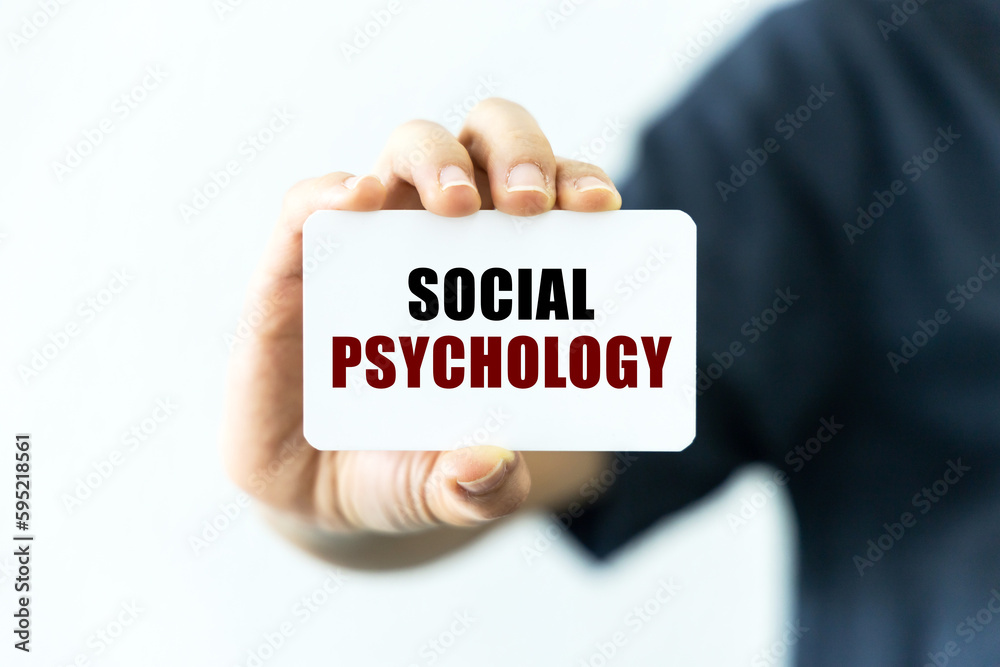 Social psychology text on blank business card being held by a woman's hand with blurred background. Business concept about social psychology. Social psychology text on blank business card being held by a woman's hand with blurred background. Business concept about social psychology.