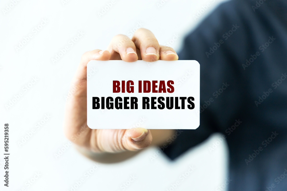 Big ideas bigger results text on blank business card being held by a woman's hand with blurred background. Business concept about big ideas bigger results. Big ideas bigger results text on blank business card being held by a woman's hand with blurred background. Business concept about big ideas bigger results.