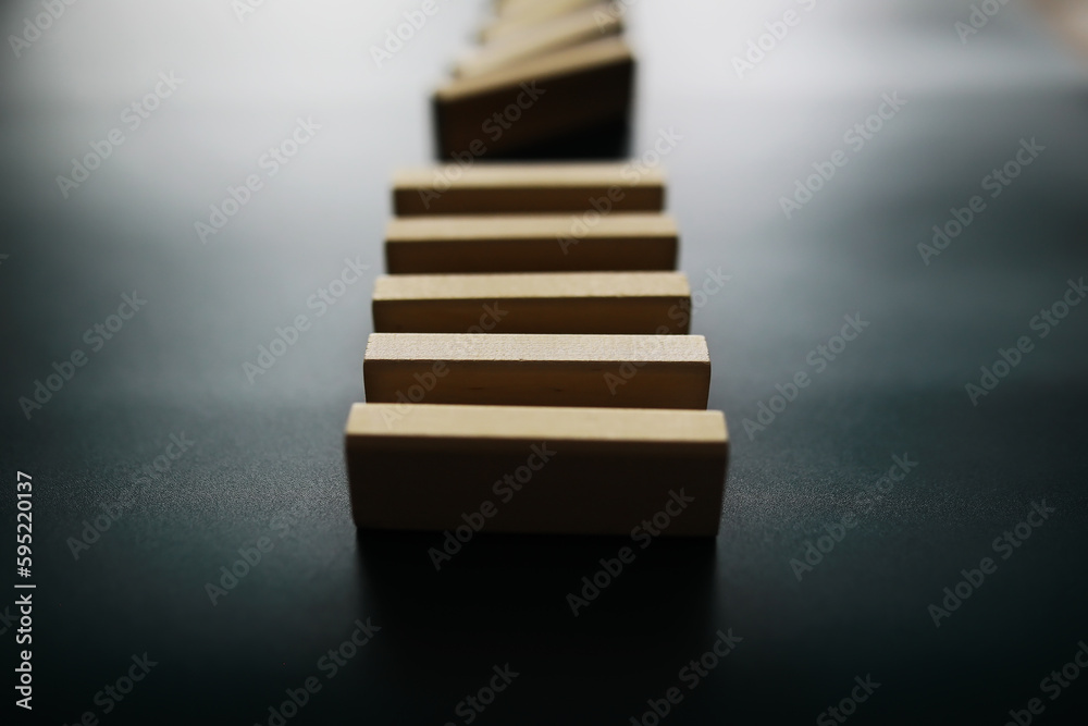 Closeup thick domino wood block in a row stop the falling, be stable in crisis, business solution concept Closeup thick domino wood block in a row stop the falling, be stable in crisis, business solution concept