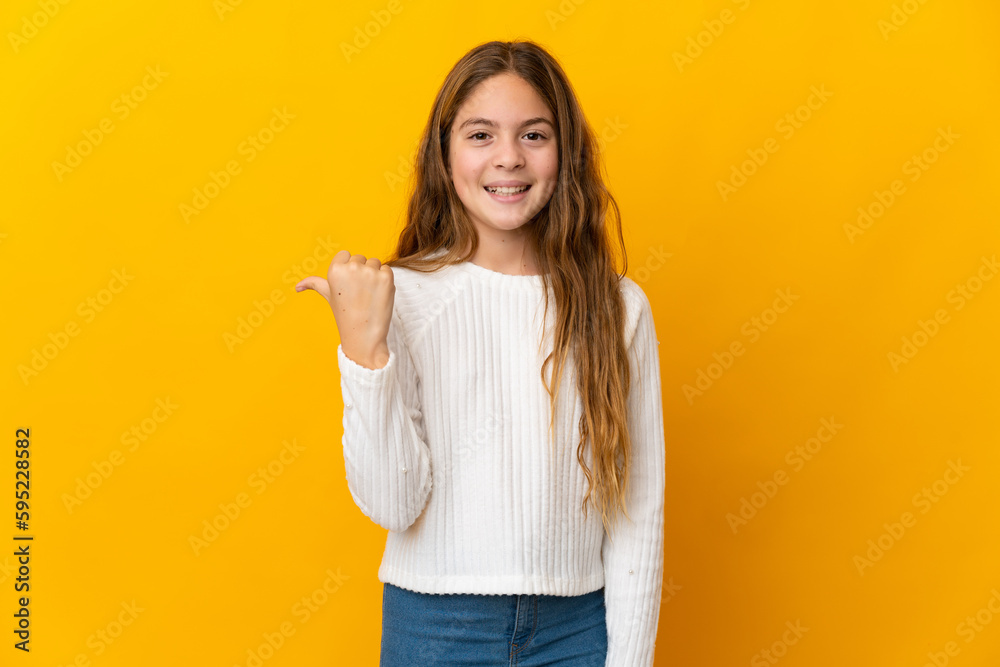Child over isolated yellow background pointing to the side to present a product Child over isolated yellow background pointing to the side to present a product