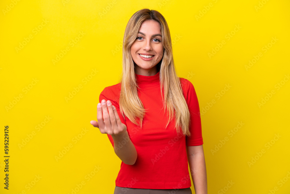 Young Uruguayan woman isolated on yellow background inviting to come with hand. Happy that you came Young Uruguayan woman isolated on yellow background inviting to come with hand. Happy that you came
